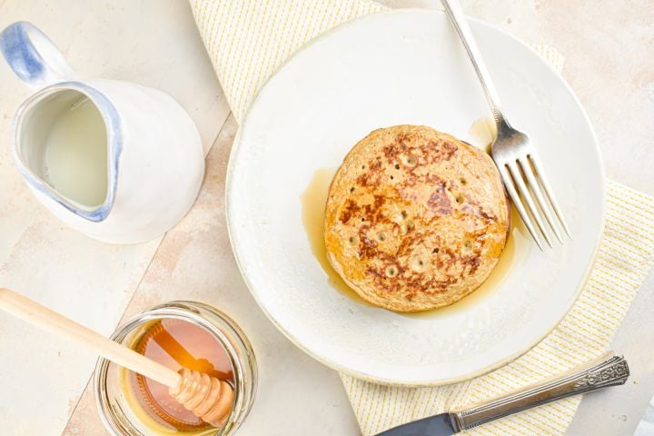 Banana flax pancakes on a plate with syrup on the side.