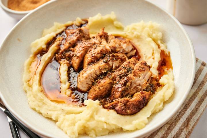 Air fryer turkey breast tenderloin with herbs and sauce on a plate with mashed potatoes.
