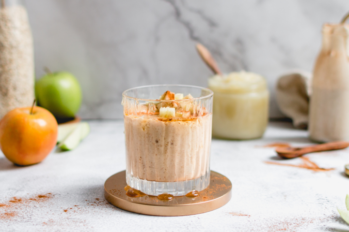 Apple banana smoothie with cinnamon, apples, bananas, and oats in a glass with apples on the side.