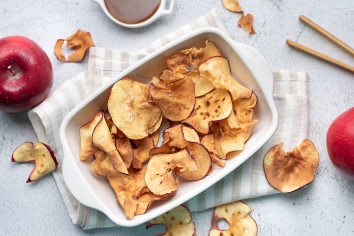 Apple chips with cinnamon that are baked until crispy in a ceramic dish.