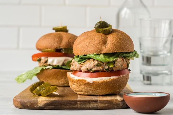 Asian turkey burgers with lettuce, tomato, and sweet chili yogurt sauce on two buns,