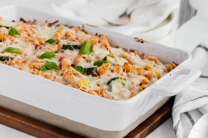 Roasted Vegetable Baked Ziti with melted cheese in a white casserole dish.