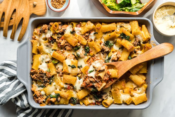 Baked ziti with ground beef, tomatoes, zucchini, and melted cheese in a baking dish.