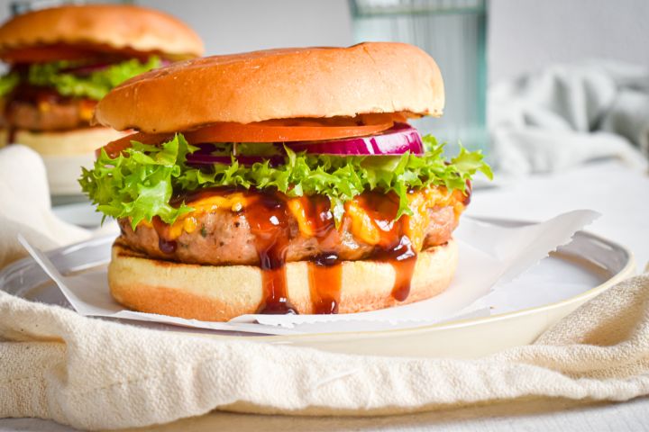 Barbecue cheddar turkey burgers made with lean ground turkey on a roll with lettuce. red onion, and tomato.