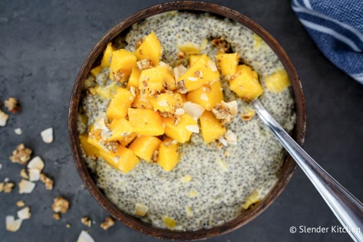Chia seed pudding with mango on top in a wooden bowl.
