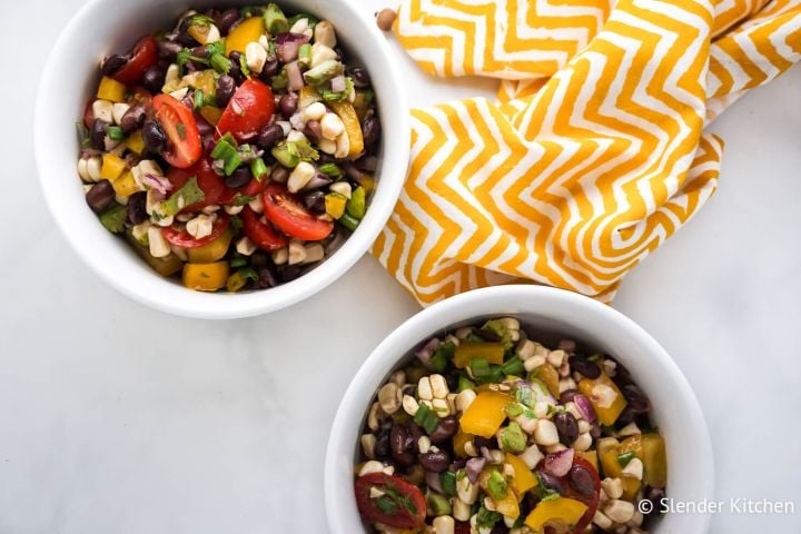 Black bean corn salad with lime dressing, canned black beans, tomatoes, corn, cilantro, and bell peppers.