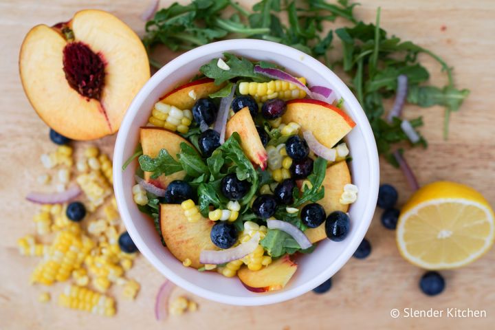 Summer salad with blueberries, corn, arugula, and nectarines in a bowl.