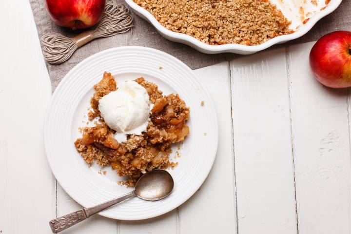 Breakfast apple crisp served on a plate with tender baked apples, an oat crumble, and yogurt.
