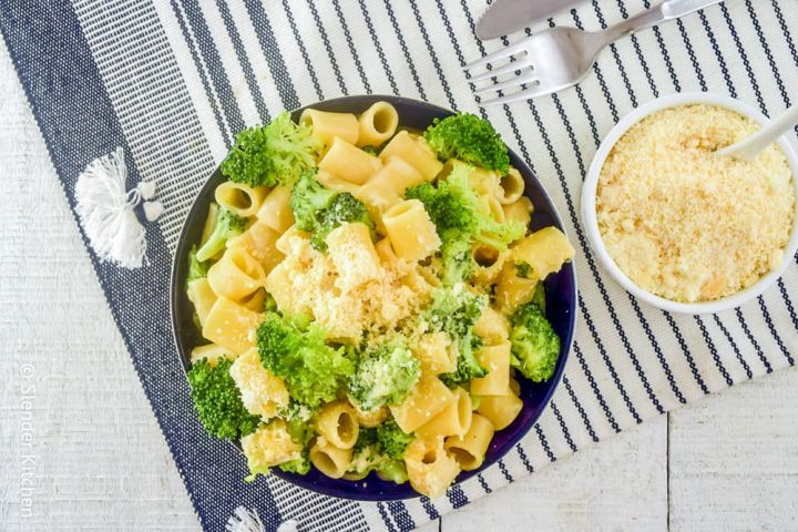 Broccoli pasta in a bowl with creamy parmesan sauce and Parmesan cheese on the side.