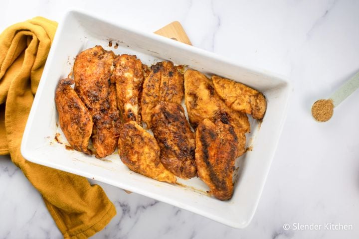 Brown Sugar Chicken in a white baking dish with extra brown sugar on the side.
