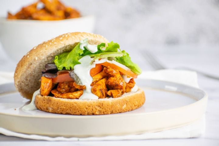 Buffalo chicken sandwich with blue cheese dressing on a bun with lettuce.