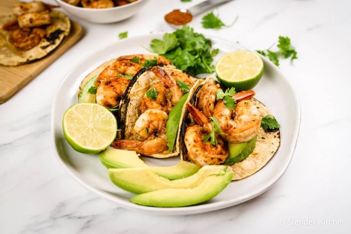 Cajun shrimp tacos in corn tortillas with sliced avocado, cilantro, and fresh lime juice.