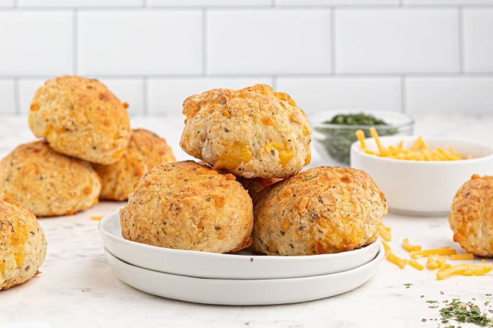 Cheddar biscuits baked until golden brown piled on a plate.