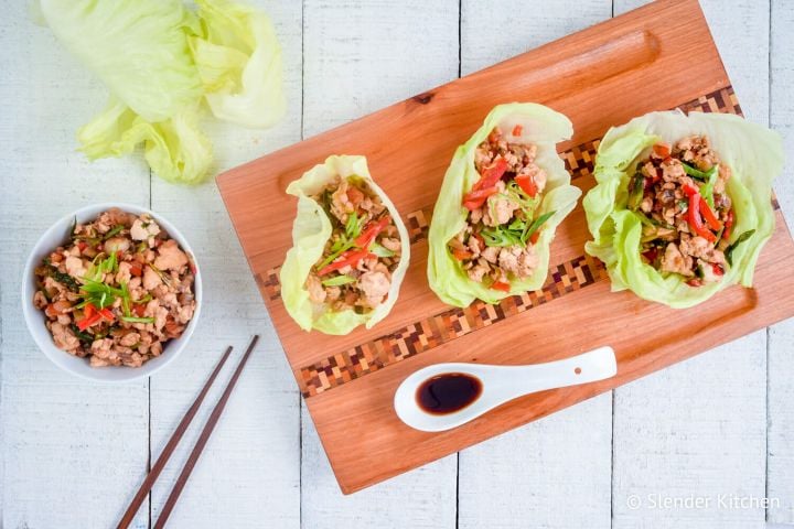 Chicken lettuce wraps on a wooden board with ground chicken and veggies in a hoisin sauce.