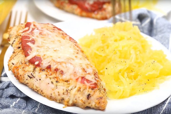 Spaghetti squash chicken parmesan on a plate with a blue napkin and fork.