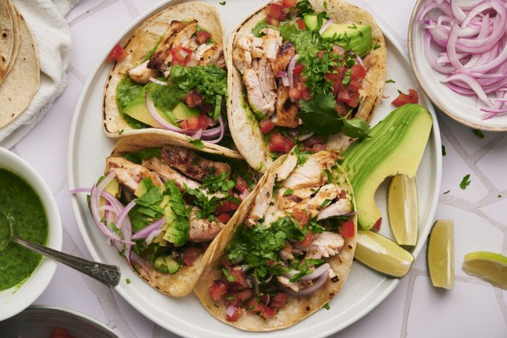Chicken street tacos with grilled chicken thighs, fresh cilantro, onion, salsa, and lime served on corn tortillas.