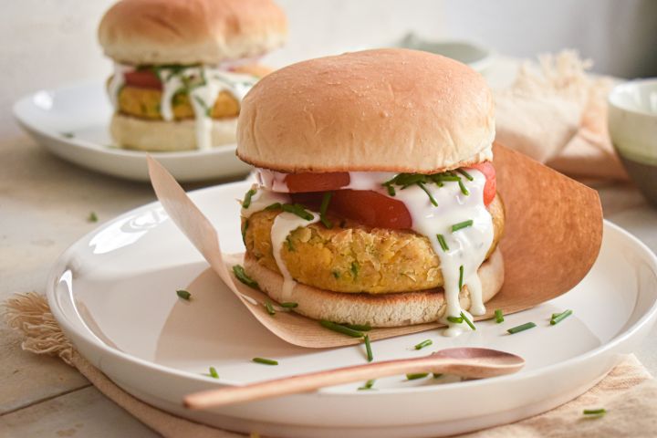 Ranch chickpea burgers served on a bun with lettuce, tomato, and ranch dressing. 