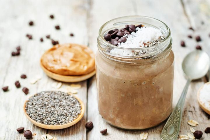 Chocolate peanut butter chia seed pudding served in a glass jar with peanut butter and chia seeds on the side.