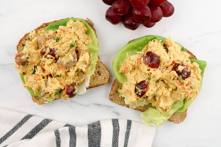 Curry tuna salad on whole wheat toast with lettuce and red grapes.