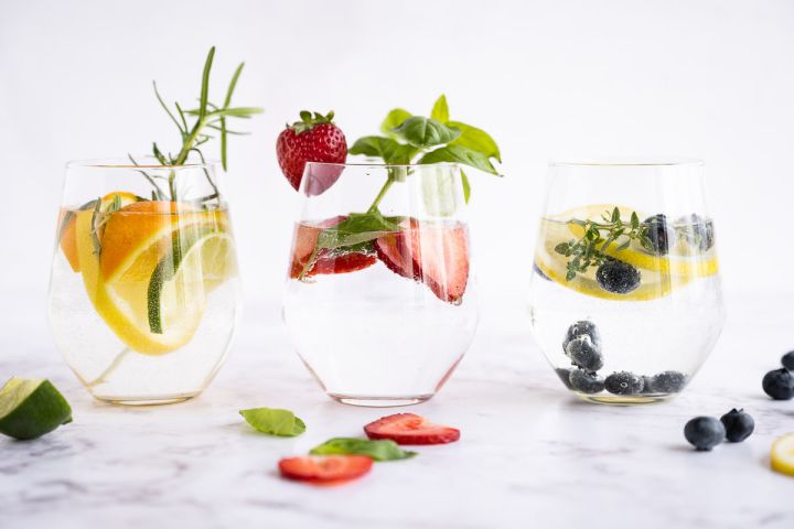 Detoz water in a glass with lemon, lime, and orange slices with rosemary sprigs.