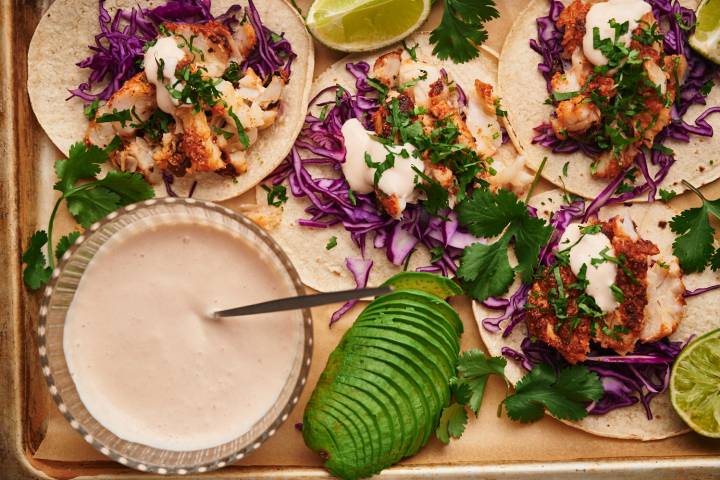 Fish taco sauce in a bowl and served drizzled over fish tacos with cabbage, cilantro, and avocado.