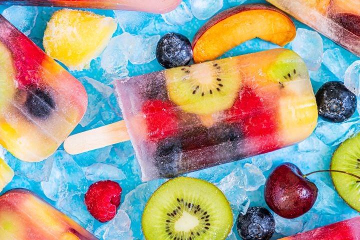 Fresh fruit popsicles made with kiwi, raspberries, peaches, cherries, blueberries, and coconut water.