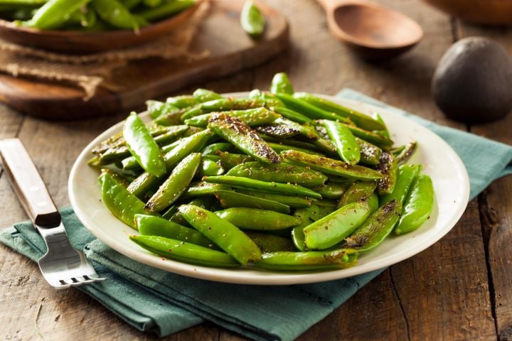 Garlic snap peas lightly browned and piled onto a plate.