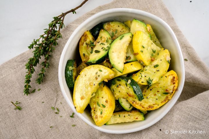 Sauteed zucchini and summer squash with fresh thyme and garlic in a bowl.