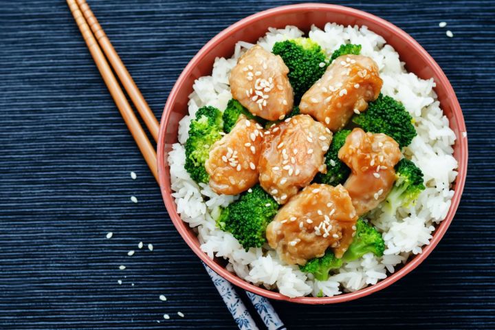 General Tso's pork with lightly breaded pork and broccoli served over white rice in a bowl.