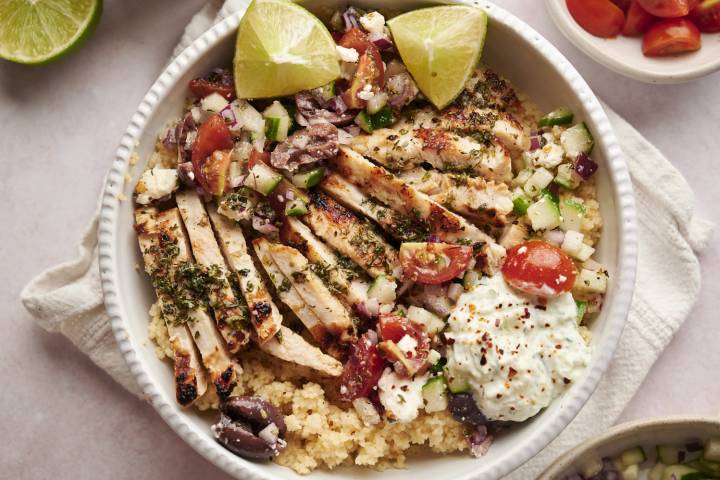 Greek chicken bowls with grilled chicken, tomatoes, cucumbers, red onions, feta cheese, red onions, and quinoa. 