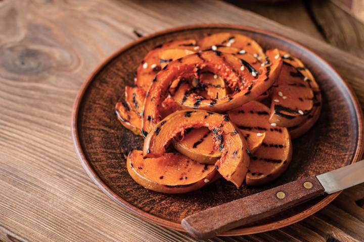 Grilled acorn squash on a plate with caramelized edges. 