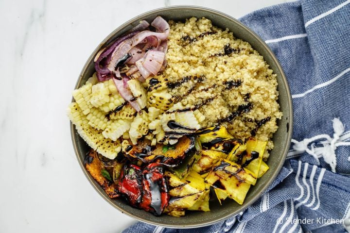 Balsamic grilled vegetables with peppers, summer squash, corn, and onions with quinoa in a bowl.