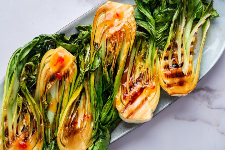 Grilled bok choy with sweet chili sauce served on a plate. 