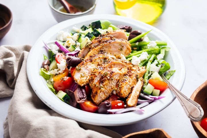 Grilled chicken Greek salad with black olives, feta cheese, tomatoes, Romaine lettuce, and red onions in homemade dressing.