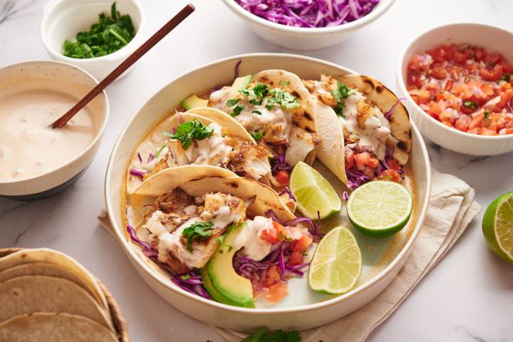 Grilled fish tacos with grilled white fish, shredded cabbage, avocado, pico de gallo, and creamy white fish taco sauce.