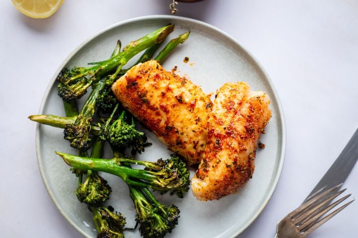 Grilled red snapper with homemade spice rub on a plate with grilled broccoli.