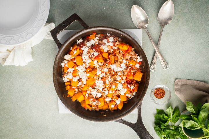 Ground turkey and butternut squash skillet with tomatoes and fresh herbs in a ceramic baking dish.