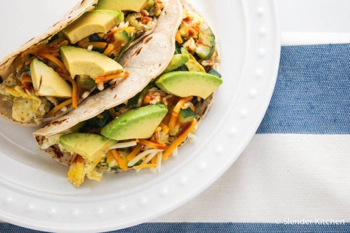 Healthy breakfast tacos with black beans, eggs, avocado, and salsa in corn tortillas.