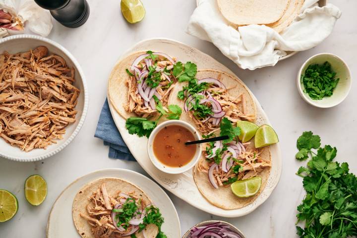 Healthy carnitas tacos with shredded pork, cilantro, and onion served in corn tortillas.