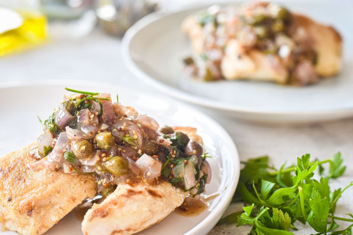 Healthy chicken piccata on a plate with a garlic, butter, and caper sauce.