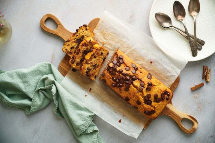 Healthy pumpkin chocolate chip bread sliced and served on a wooden cutting board.