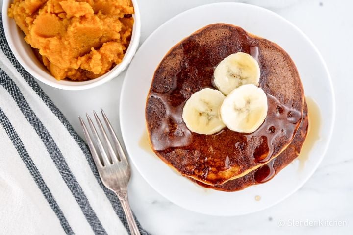Healthy Pumpkin Pancakes on a white plate with butter and maple syrup.