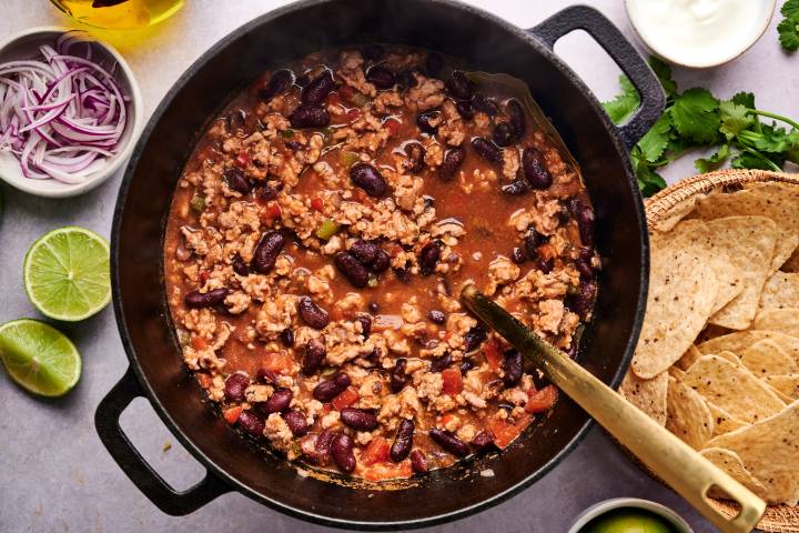 Healthy turkey chili in a soup pot woith ground turkey, kidney beans, peppers, onions, and tomatoes. 