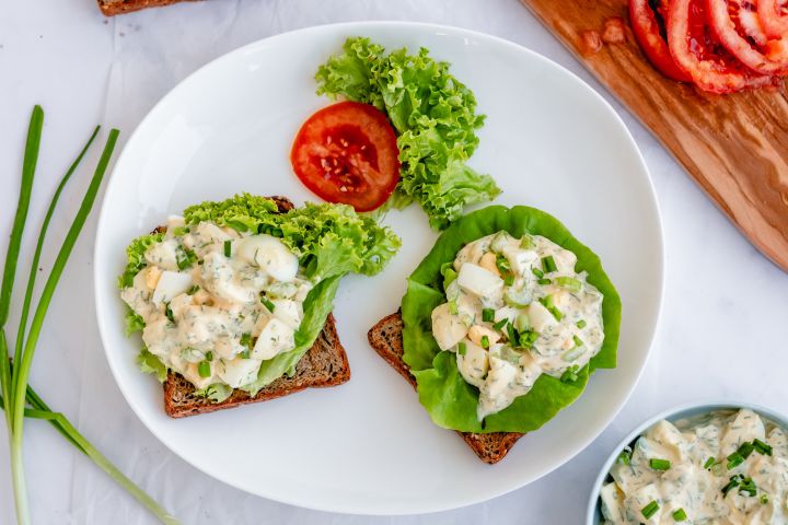 Healthy egg salad with fresh herbs, Greek yogurt, and hard boiled eggs on whole wheat bread.