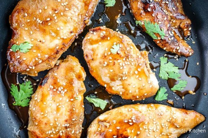 Honey soy chicken on a baking sheet with cilantro and sesame seeds.