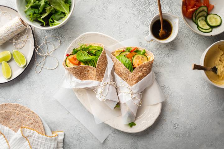 Hummus wrap with mixed greens, tomatoes, cucumbers, avocado, carrots, and bell peppers in whole wheat tortillas.