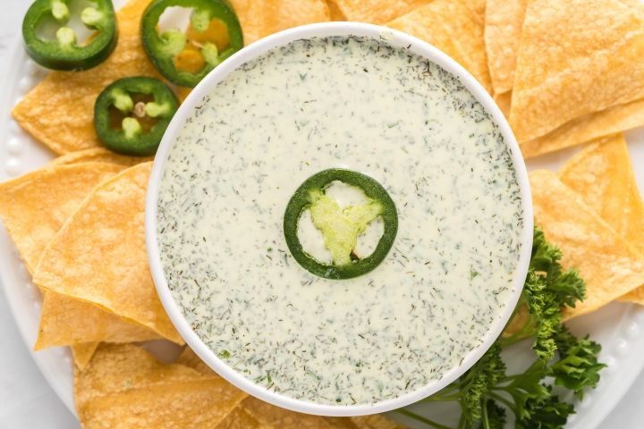 Jalapeno ranch dressing with Greek yogurt, herbs and jalapenos in a small dish with chips on the side.