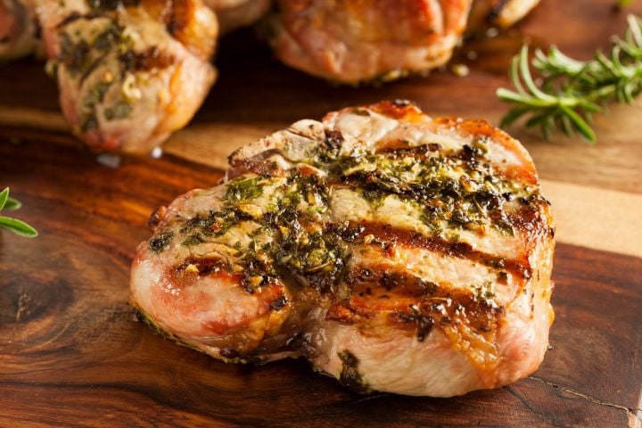 Lemon basil pork chops cooked on the grill with extra basil garlic sauce drizzled on top. 