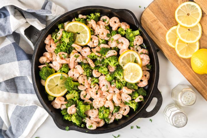 Lemon pepper shrimp and broccoli in a cast iron skillet with garlic, shrimp, and brocoli florets.