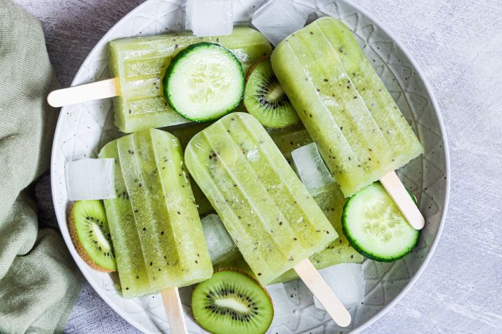 Mexican cucumber paletas with fresh kiwi and cucumber served on a plate with ice.